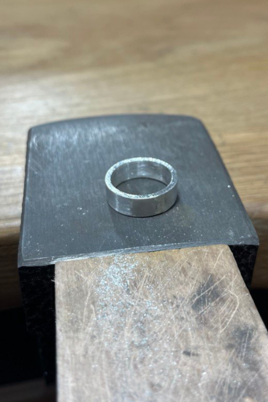 Unpolished silver ring on a bench block, jewelry-making process